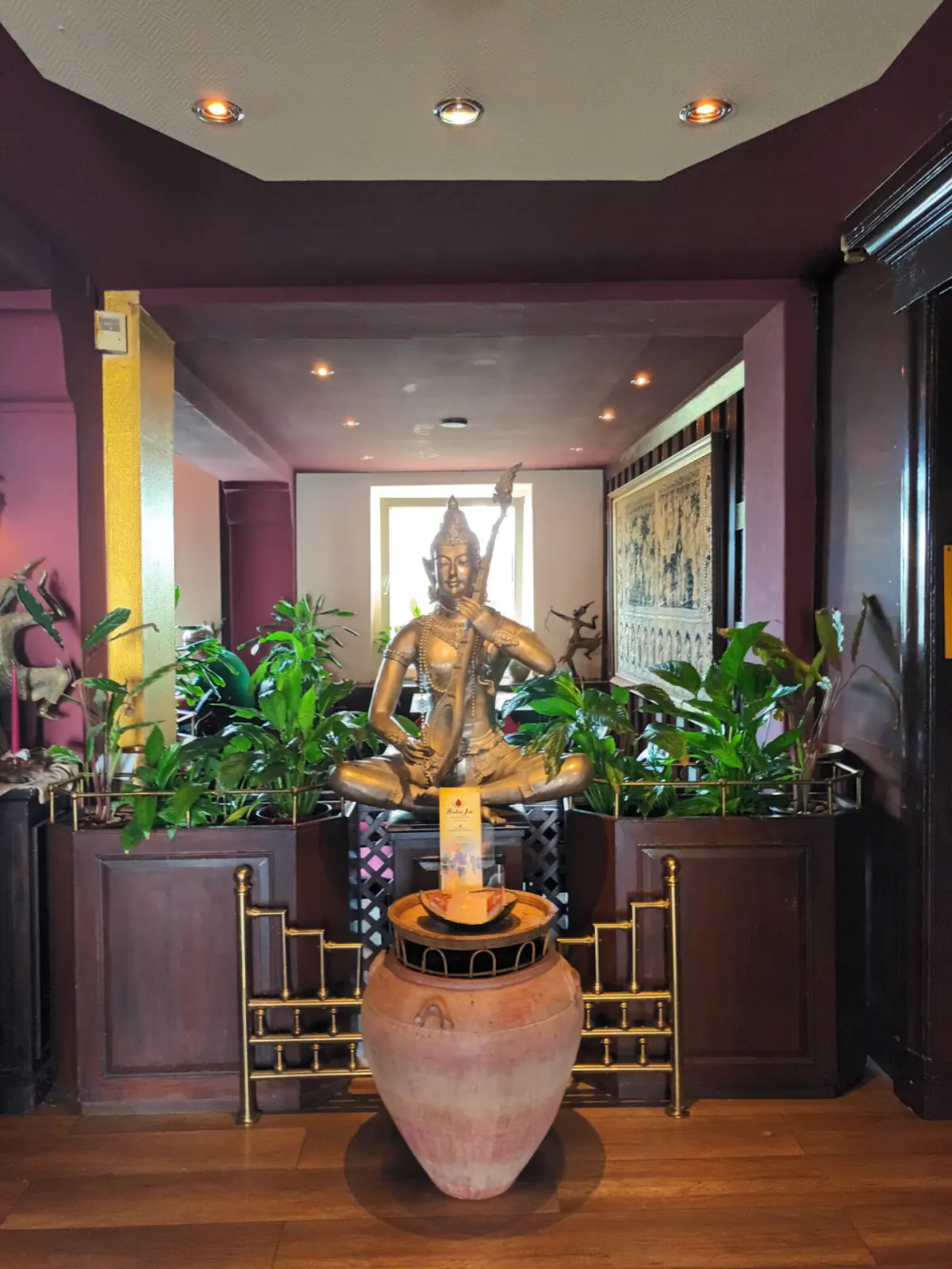 Eingangsbereich mit vergoldeter Buddha-Figur zwischen Pflanzen